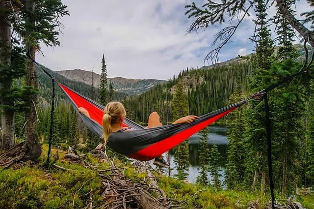A person relaxes in a hammock overlooking a mountain lake, enjoying the peace of mind that comes with our Canmore property management.