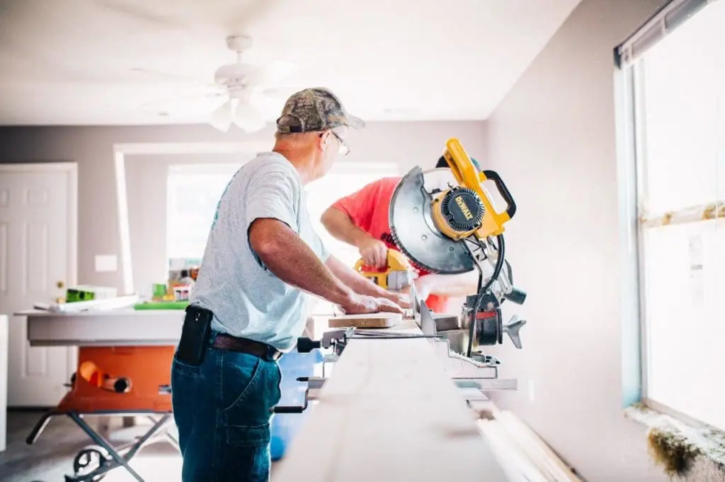 Two men operating a table saw in a workshop.