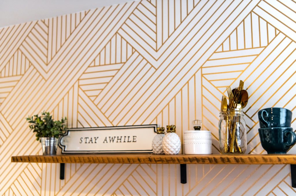 A shelf against a gold and white wallpaper background.